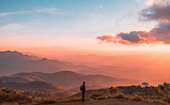 Trekker admiring the sunrise over the hills of Chiang Mai, Thailand. Colton Duke@Unsplash