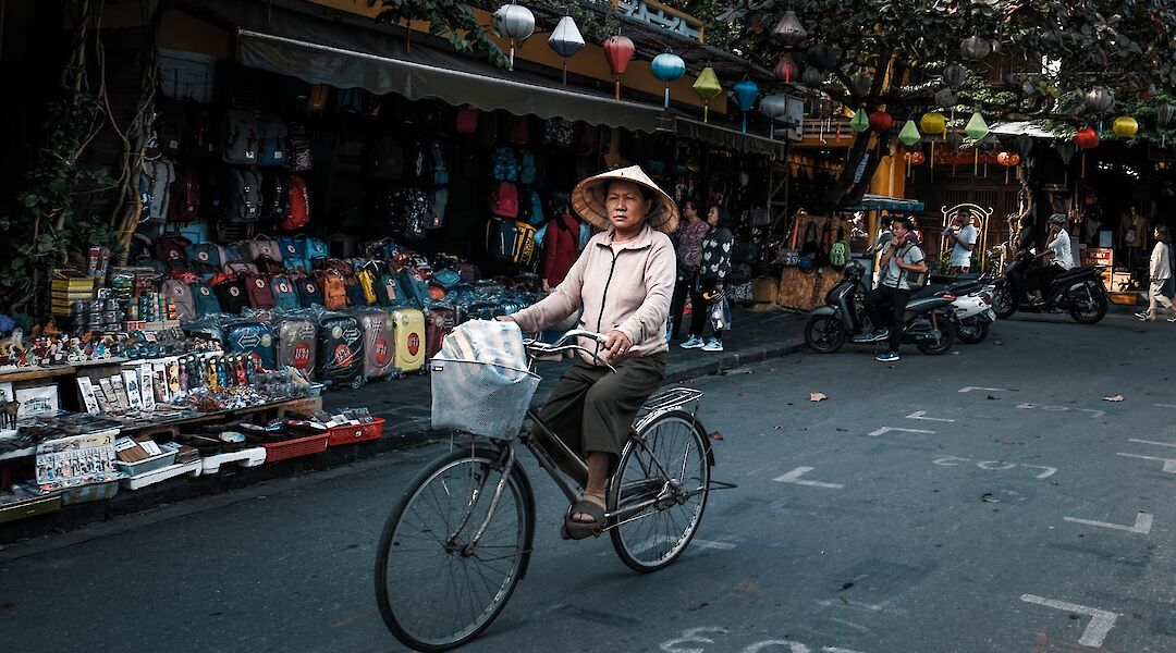 Local lady biking through the market, Hoi An, Vietnam. Minh Pham@Unsplash