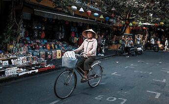 Local lady biking through the market, Hoi An, Vietnam. Minh Pham@Unsplash