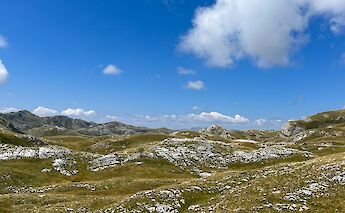 blue skies and white clouds over the hilly terrain of Zabljak, Montenegro. Ilse@Unsplash
