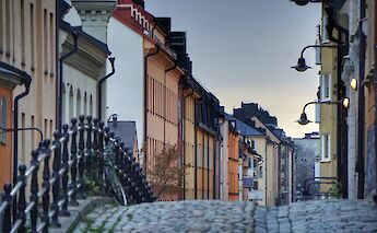 Cobbled street in Södermalm, Stockholm, Sweden, lined with colorful buildings and ornate street lamps.