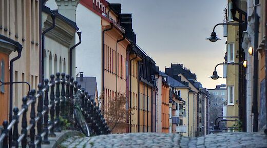 Cobbled street in Södermalm, Stockholm, Sweden, lined with colorful buildings and ornate street lamps.