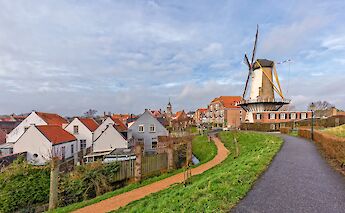 A picturesque view of Willemstad in the Netherlands, featuring a traditional windmill and quaint houses with red roofs.