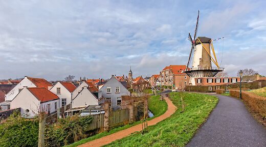 A picturesque view of Willemstad in the Netherlands, featuring a traditional windmill and quaint houses with red roofs.