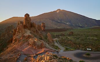 Rock formations and a mountainous landscape with Mount Teide in the background at sunset, in Tenerife, Spain.