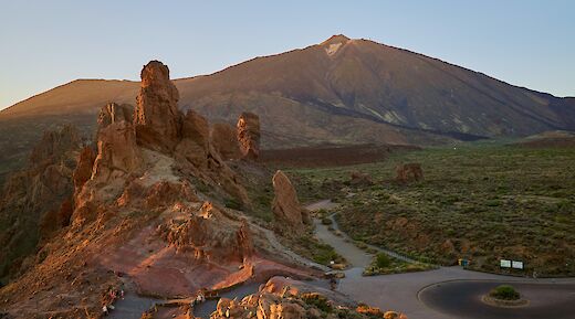 Rock formations and a mountainous landscape with Mount Teide in the background at sunset, in Tenerife, Spain.