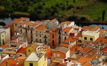 Aerial view of colorful buildings with terracotta roofs by a river in the old town of Bosa, Sardinia, Italy.