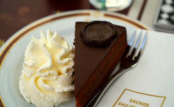 Sachertorte served with cream, Austria. Unsplash:Tim Photoguy
