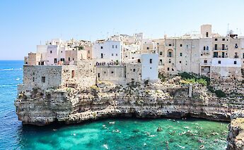 Swimming in the turquoise waters beneath the cliffs of Polignano a Mare, with historic buildings above.