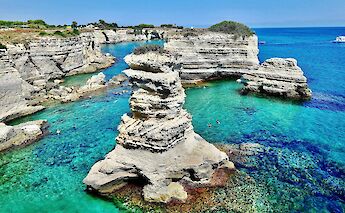Rock formations and clear turquoise waters along the coastline in Salento, Italy.