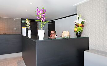 A reception area on the boat Arkona with a black counter, decorated with vibrant flower vases.