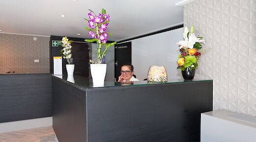 A reception area on the boat Arkona with a black counter, decorated with vibrant flower vases.