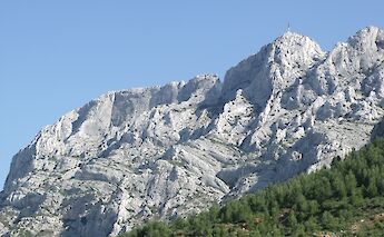Rocky limestone mountain ridge of Montagne Sainte-Victoire under a clear blue sky, Aix-en-Provence, France.