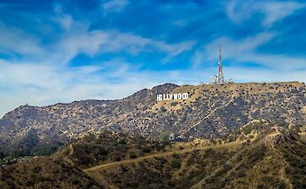 The Hollywood Sign atop a rugged hillside under a bright blue sky in Los Angeles, California.
