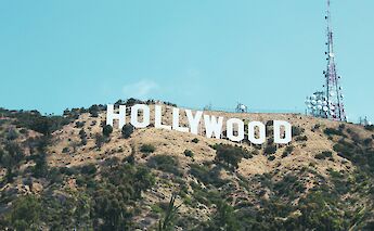 The Hollywood Sign on a hillside with communication towers nearby, under a clear blue sky in Los Angeles, California.
