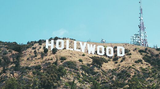 The Hollywood Sign on a hillside with communication towers nearby, under a clear blue sky in Los Angeles, California.