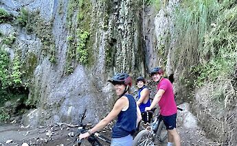 Three people with mountain bikes are posing in front of a waterfall, surrounded by lush greenery&hellip;
