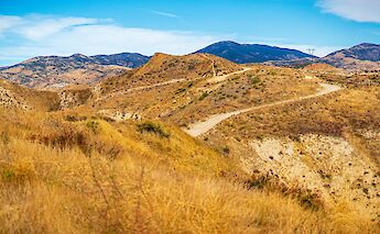 A winding dirt trail through arid, rolling hills under a blue sky in Santa Clarita, California.