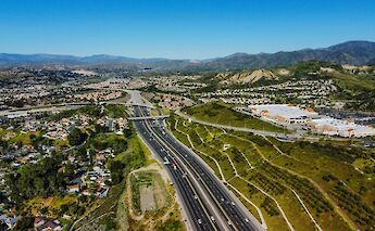 A highway cutting through green hills with residential and commercial areas in Santa Clarita, California.
