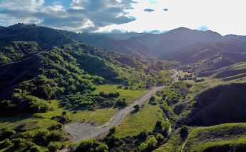 Aerial view of lush, green hills and a winding road in Santa Clarita, California.