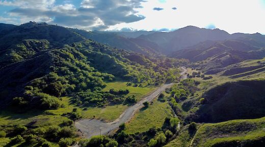 Aerial view of lush, green hills and a winding road in Santa Clarita, California.