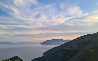 A scenic view from Alonissos overlooking the Aegean Sea with mountainous terrain and a colorful sky.