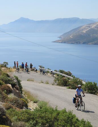 Cyclists on a coastal road overlooking the Sporades Islands and the Aegean Sea.