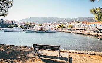 Skiathos Beach in Greece, showing a waterfront with parked boats and colorful buildings in the background.
