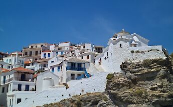 Skopelos Town in Greece, featuring traditional whitewashed houses with red-tiled roofs, situated on a rocky hillside.