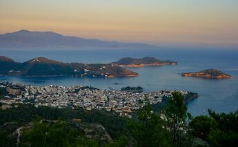 View of Skiathos Town and surrounding islands at sunset with the Aegean Sea in the background.