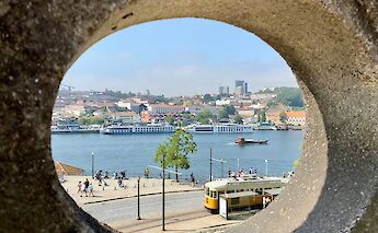 A tram seen through a hole in a building, Porto, Portugal bike tours. Rikin Katyal@Unsplash
