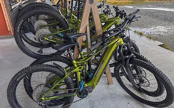 A row of green e-mountain bikes parked under a shelter in Voss, Norway.