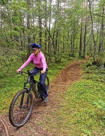 A person on an e-mountain bike navigating a forest trail in Voss, Norway.
