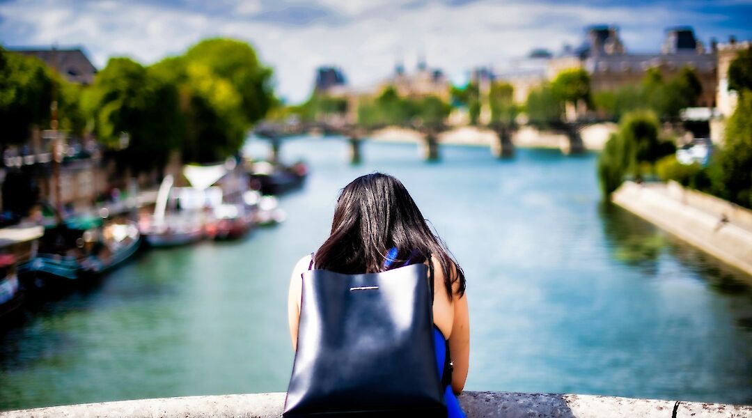 Woman leaning over a bridge, Paris, France. Clement Souchet@Unsplash