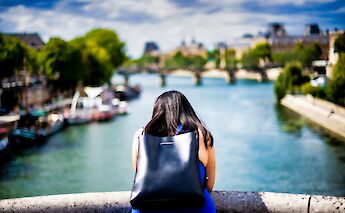 Woman leaning over a bridge, Paris, France. Clement Souchet@Unsplash