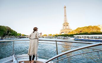 Woman looking at the Eiffel Tower from a boat on the Seine River, Paris. Getty Images@Unsplash