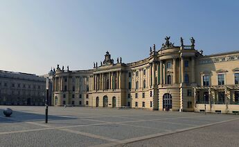 The historic Bebelplatz in Berlin, Germany, featuring a neoclassical building with statues and architectural details.
