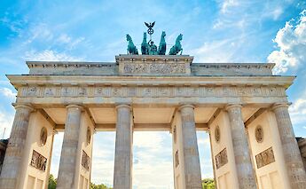 A view looking up at the Brandenburg Gate in Berlin, Germany, with the sky visible above.
