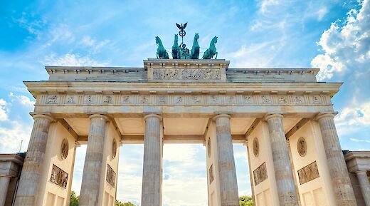 A view looking up at the Brandenburg Gate in Berlin, Germany, with the sky visible above.