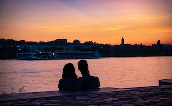 Couple sitting next to the Rhine at sunset, Mainz, Germany. Unsplash:Michael Behrens