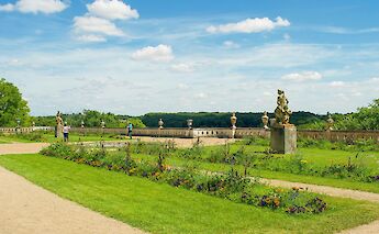 The gardens of Fontainebleau Castle in France, featuring vibrant flowers, statues, and a scenic view of the surrounding landscape.
