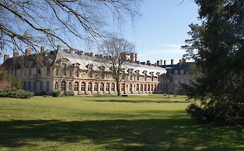 View of the Château de Fontainebleau and its gardens, surrounded by green lawns and trees.