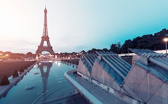 The Eiffel Tower in Paris, France, viewed from the Trocadéro Gardens, reflecting in the water at sunset.