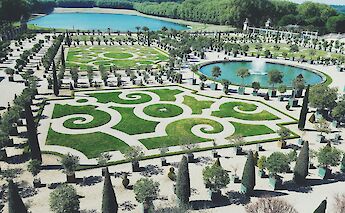 Patterned gardens in Versailles, featuring manicured lawns and a fountain.