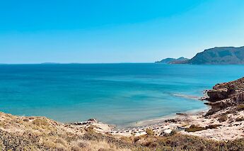 A scenic bay on Kos Island, Greece, with clear blue waters and distant hills.