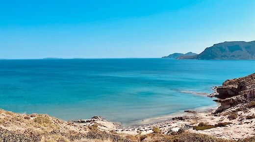 A scenic bay on Kos Island, Greece, with clear blue waters and distant hills.