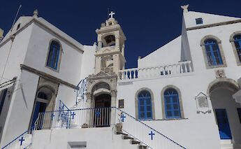 A whitewashed building with blue doors and windows against a clear blue sky, located in Nikia on the island of Nisyros, Greece.