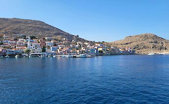 View of the Island of Chalki from the sea, showing colorful buildings along the waterfront in Greece.