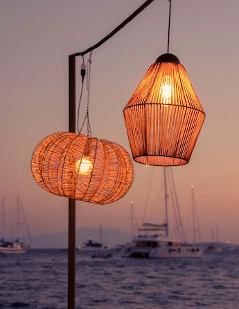Two illuminated lanterns at sunset in Bodrum, Turkey, overlooking the sea with boats in the background.