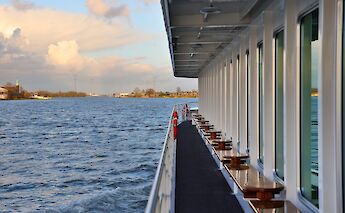 The side view of the boat "Lisabelle," showing a walkway alongside windows, with a river&hellip;